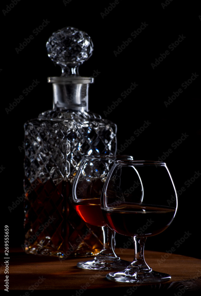 Brandy or cognac in glasses and a decanter on a brown wooden background Brandy or cognac in glasses and a decanter on a brown wooden background