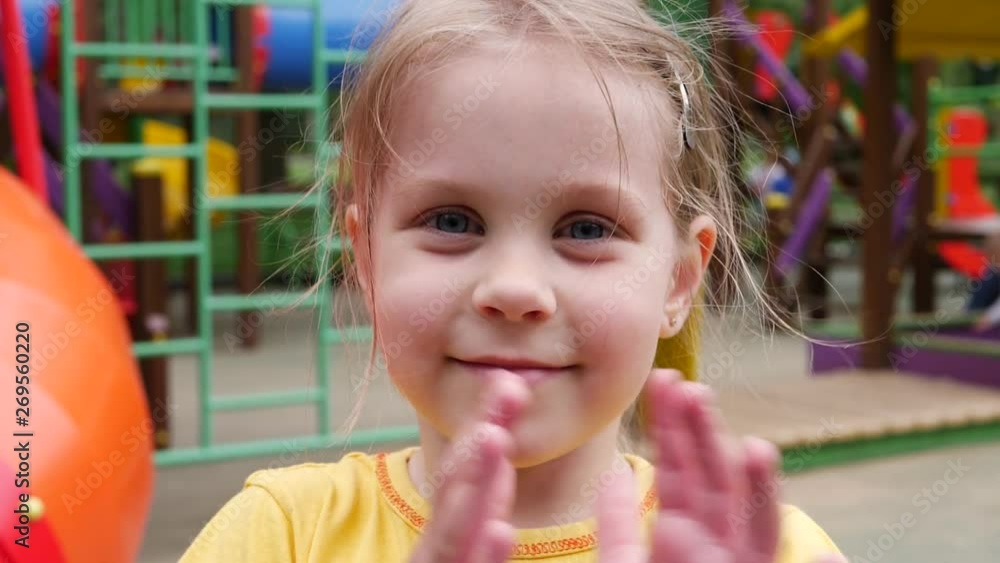 Little child girl in yellow t-shirt having fun to clap one's hands in playground Little child girl in yellow t-shirt having fun to clap one's hands in playground