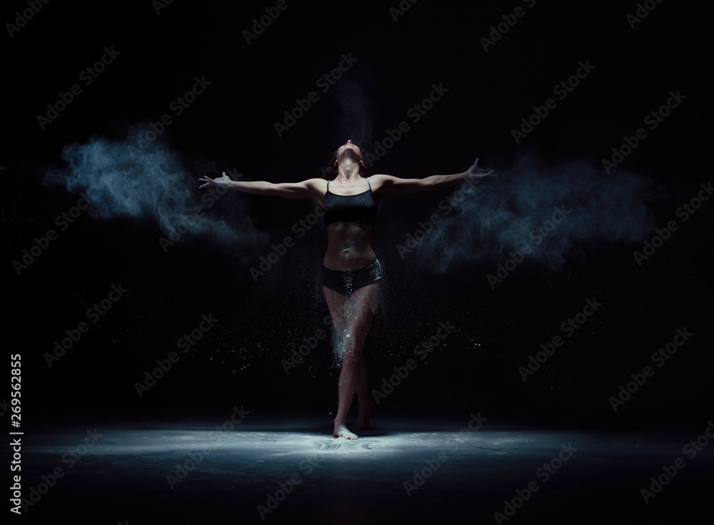 Graceful woman dancing in white dust cloud shot