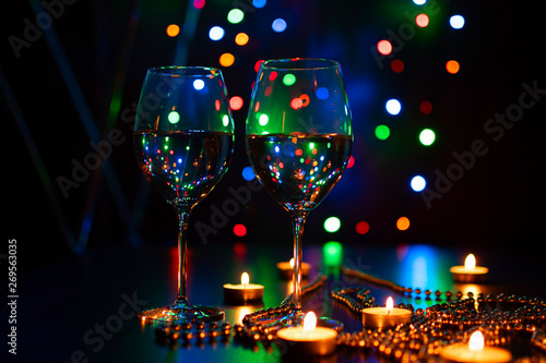 Two wine glasses and Fire of candle on christmas background. Christmas candles burning at night. Abstract candles background. Golden light of candle flame. Hope, fire. Candle lights in the darkness.