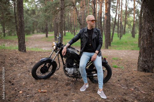 Portrait hipster young guy with a beard and mustache with sunglasses, street casual a motorcycle