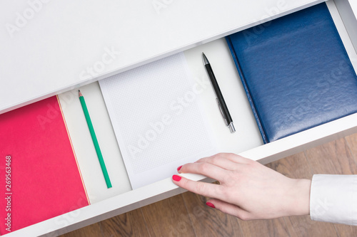 Woman open shelf with notebooks and pens, top view, copy space, advertising