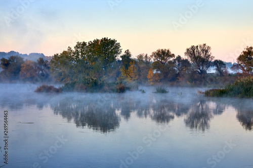 Haze over the river in the early autumn morning. Reeds mist fog and water surface on the river at sunrise