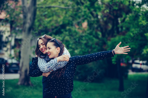 Young woman carrying her female friend on her back