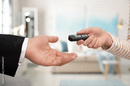 Woman giving car smart key to man indoors, closeup