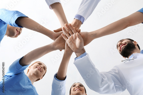 Team of medical doctors putting hands together on white background, closeup. Unity concept