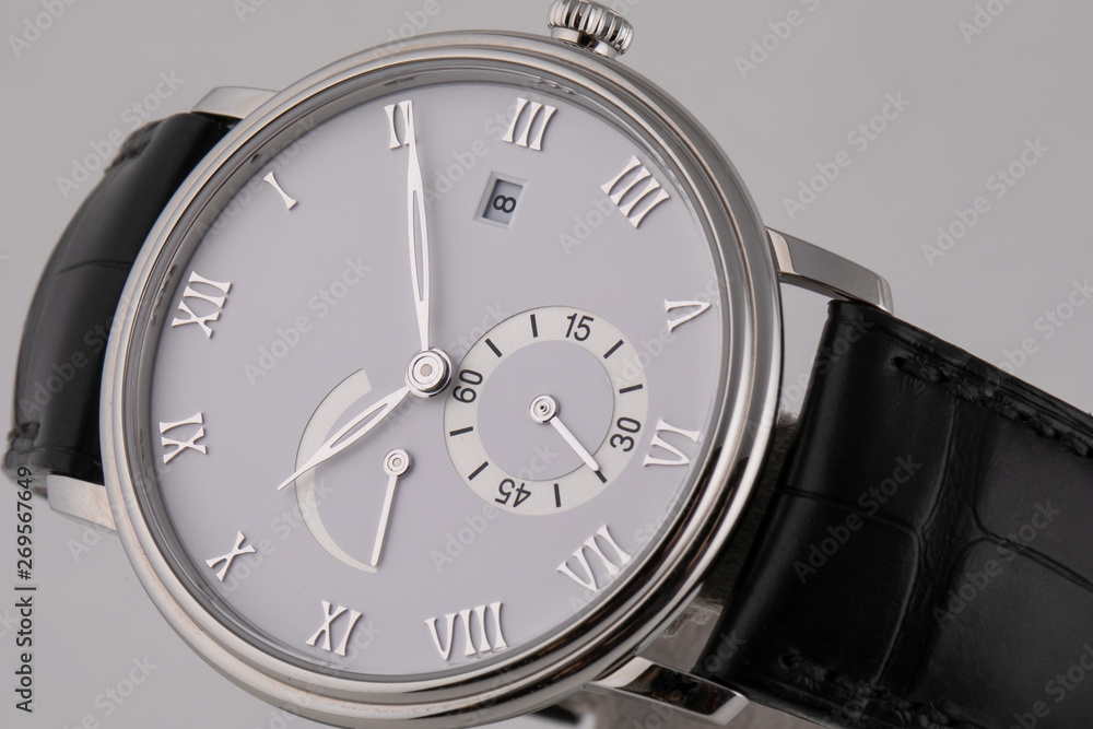 Silver wristwatch with white dial, silver clockwise, stopwatch and chronograph on black leather strap isolated on white background. Silver wristwatch with white dial, silver clockwise, stopwatch and chronograph on black leather strap isolated on white background.