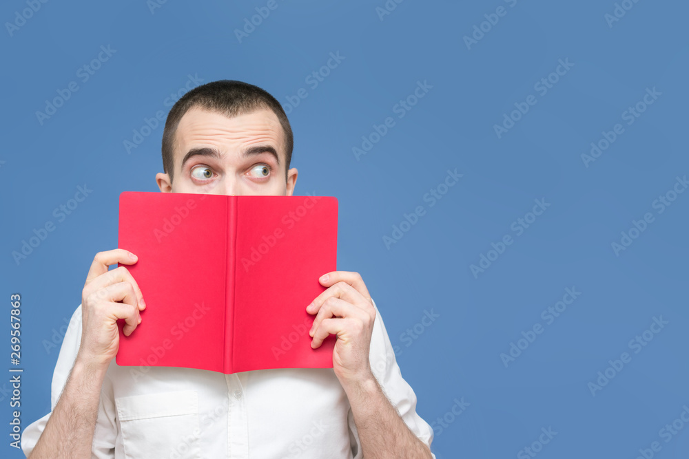 Guy is shocked after reading the book, pleasantly surprised, avert their eyes, blue background, copy space, for advertising, slogan, front view, blue background Guy is shocked after reading the book, pleasantly surprised, avert their eyes, blue background, copy space, for advertising, slogan, front view, blue background
