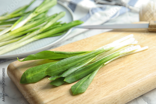 Board with wild garlic or ramson on table, closeup photo