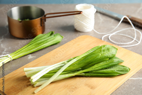 Board with wild garlic or ramson on grey table, closeup photo