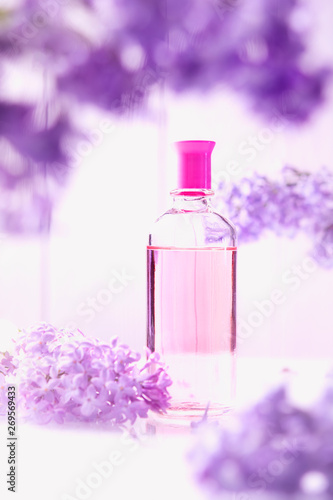 pink perfume bottle with lilac flowers on white background