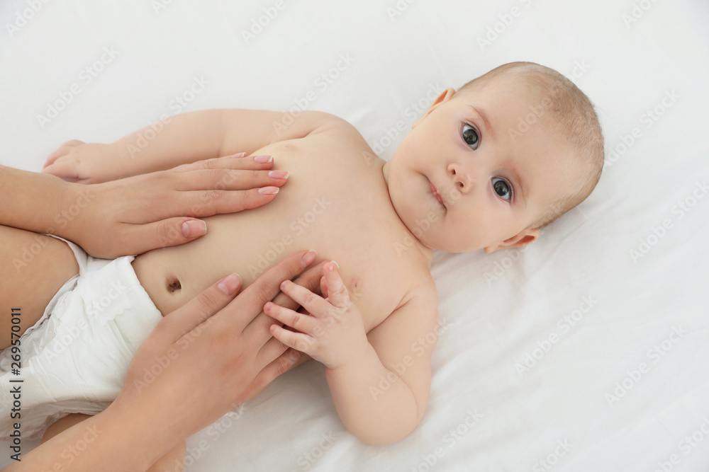 Mother and her cute child on white bed, above view. Baby massage and exercises Mother and her cute child on white bed, above view. Baby massage and exercises