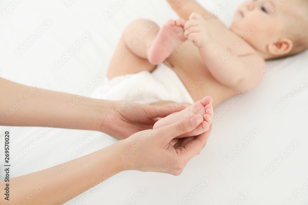 Mother and her cute child on white bed, closeup. Baby massage and exercises Mother and her cute child on white bed, closeup. Baby massage and exercises