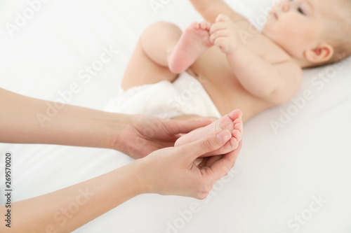Mother and her cute child on white bed, closeup. Baby massage and exercises © New Africa