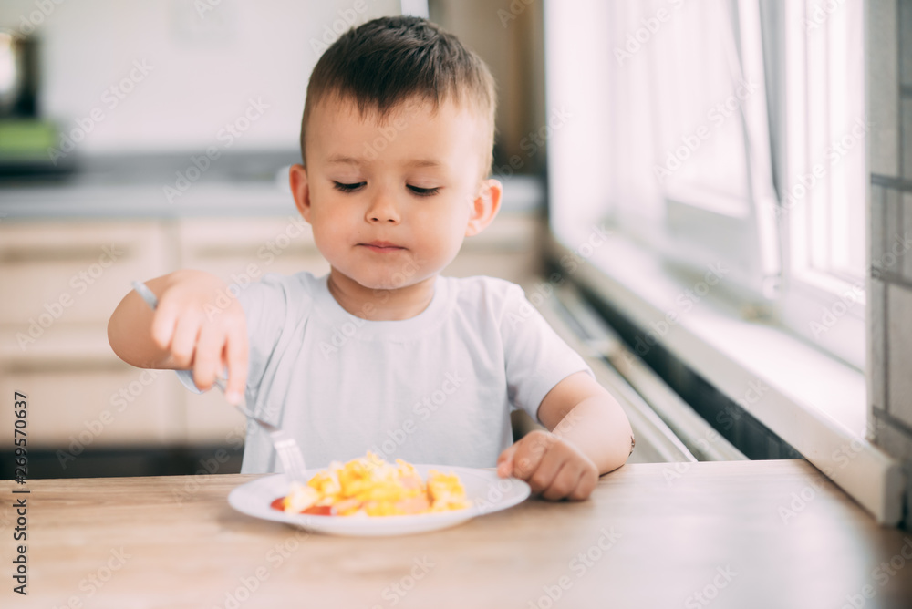 child day in the kitchen eating an omelet with sausage and ketchup child day in the kitchen eating an omelet with sausage and ketchup