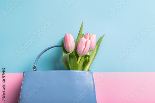 Flat lay composition with stylish woman's handbag and spring flowers on color background, space for text