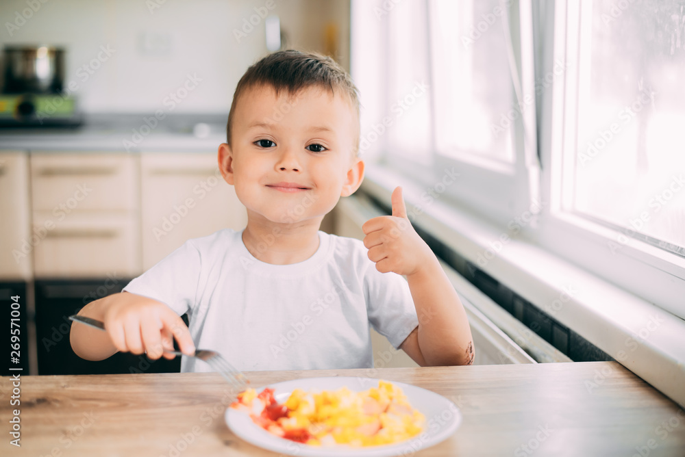 child day in the kitchen eating an omelet with sausage and ketchup child day in the kitchen eating an omelet with sausage and ketchup