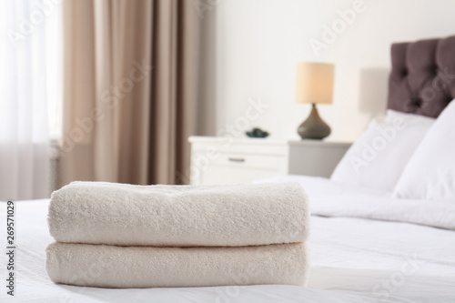 Folded soft towels on bed in room. Space for text