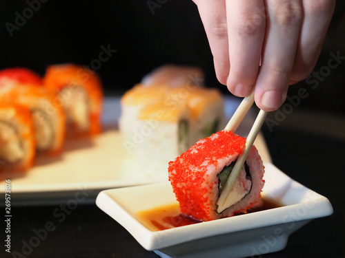 Eating sushi roll set on black background, soy sauce, close-up. Traditional Japanese oriental kitchen