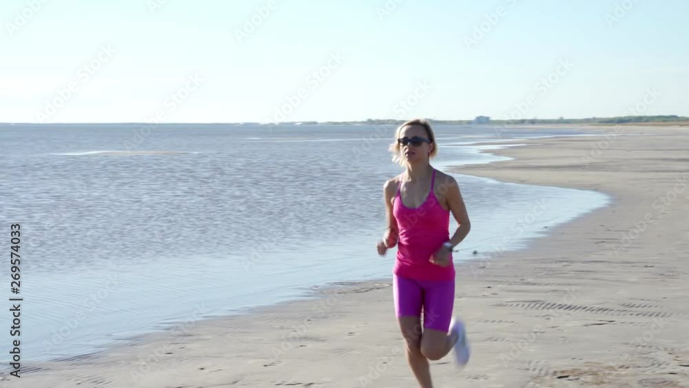 independent young woman athlete running on beach exercising female runner sprinting training in sunny seaside background