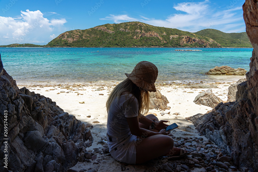 Woman using smartphone on sand beach with sea background Woman using smartphone on sand beach with sea background