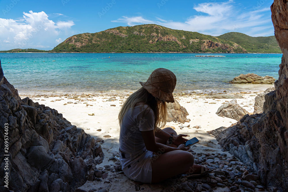 Woman using smartphone on sand beach with sea background