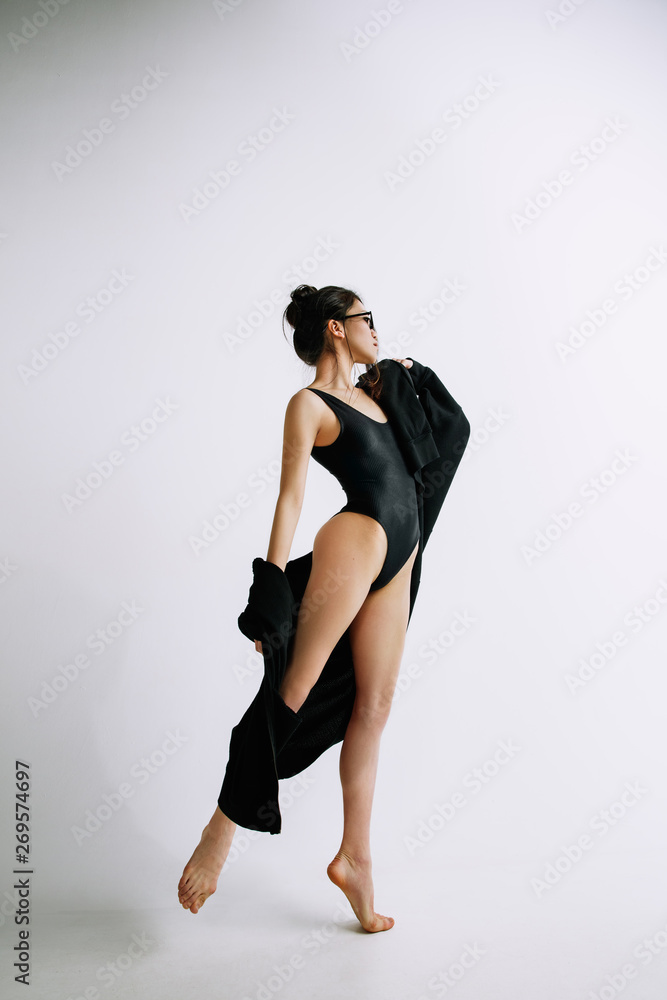 Fashion ballet. Young female ballet dancer in black bodysuit against white studio background. Asian ballerina like a fashion model. Style, contemporary choreography concept. Creative art photo. Fashion ballet. Young female ballet dancer in black bodysuit against white studio background. Asian ballerina like a fashion model. Style, contemporary choreography concept. Creative art photo.