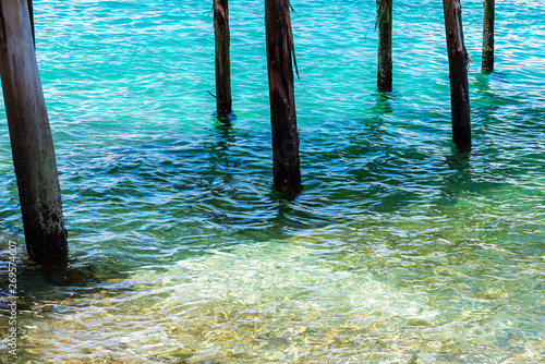 Old wooden poles in clear turquoise sea © oppdowngalon