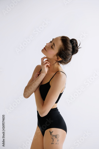 Fashion ballet. Young female ballet dancer in black bodysuit against white studio background. Caucasian ballerina like a fashion model. Style, contemporary choreography concept. Creative art photo.