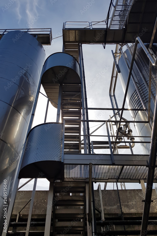Naklejka premium Stairway to the sky between metal structures and tanks..