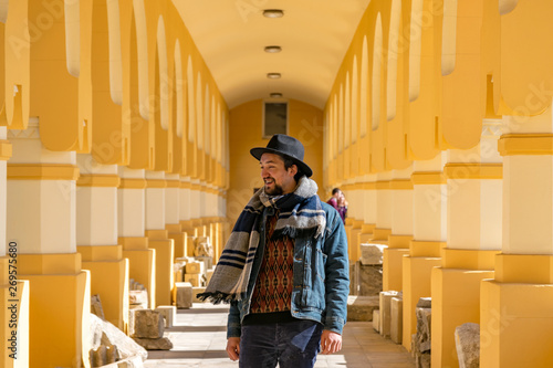 Portrait of a stylish handsome young man with a scarf outdoors.  A happy man wearing a scarf, hat and a denim jacket laughing photo