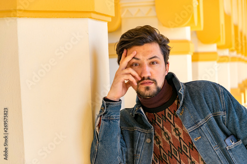 Obraz na płótnie Portrait of a stylish handsome young man with a jaket outdoors. A serious man wearing a denim jacket looking confident at the camera w salonie
