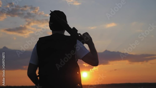 Silhouettes soldier with weapon against a sunset. photo