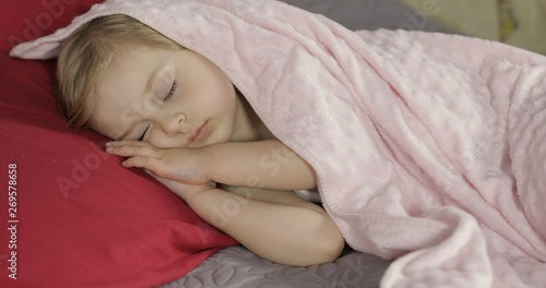 Cute baby sleeping on the bed at home. Little girl sleeping in morning light