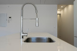 Modern curved faucet in a white kitchen with modern materials and equipment