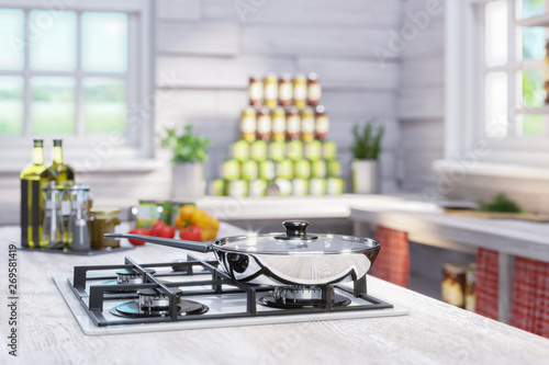 A new gas cooker and a shiny chrome-plated frying pan in a rustic wooden interior with large windows. Around cans with preserves and spices