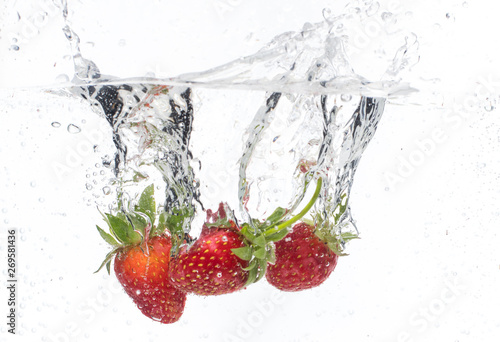 ripe red strawberries are thrown and dropped into sparkling water  many bubbles