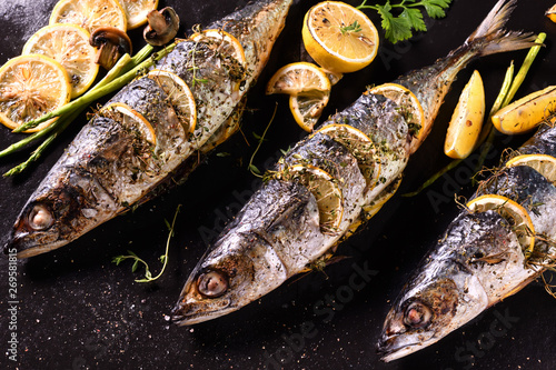 Grilled fish and various vegetables on iron plate background