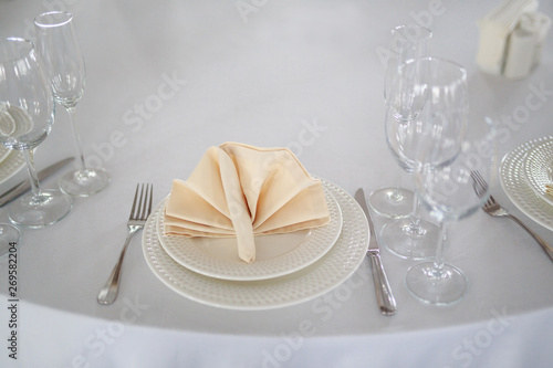 table setting, glasses are on the table, napkins in napkins beige, appliances fork knife, white clean plates, the table is set before the event