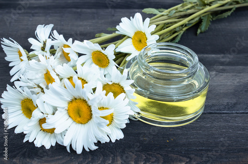 On the boards near the chamomile flowers there is a bank of light chamomile essential oil.