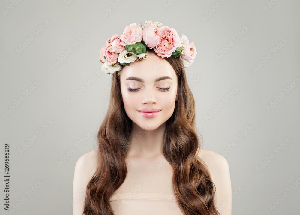 Natural beauty. Pretty woman enjoying. Model girl with clear skin, long brown curly hair and flowers