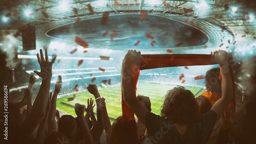 Football scene at night match with with cheering fans at the stadium