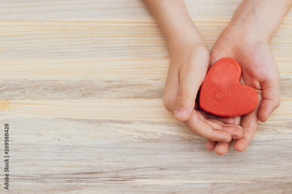 Little boy holds red heart in his hands. Love and family concept. Health care concept. International Heart Day background with copy space. Little boy holds red heart in his hands. Love and family concept. Health care concept. International Heart Day background with copy space.