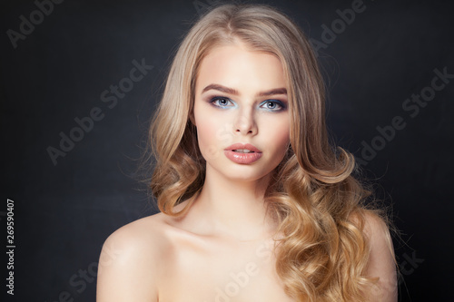 Cute woman with blonde curly hair on dark background