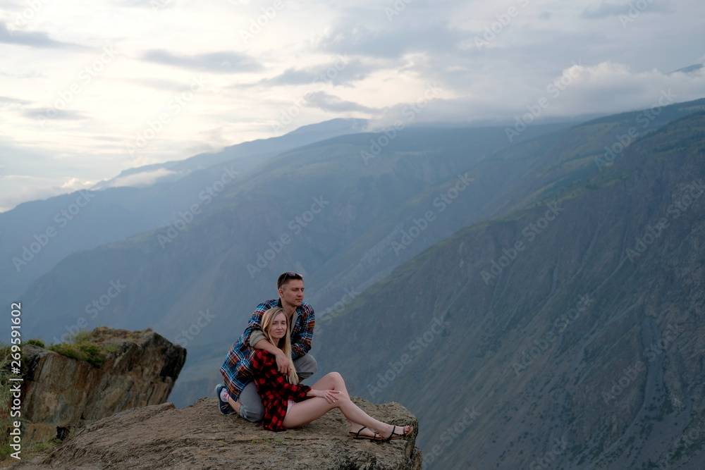 A beautiful, young boy and girl are sitting on a mountain ledge.Traveling couple