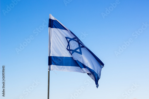 Israeli flag evolving in a wind on blue sky background, political country sign and symbols concept photography 