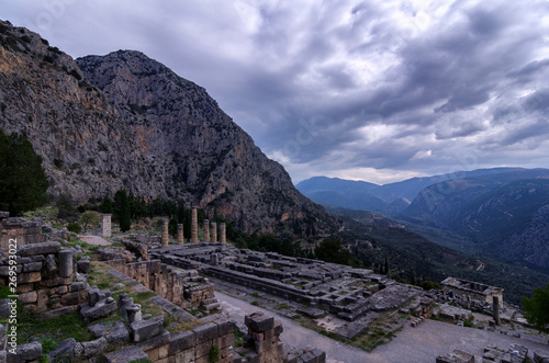 Delphi, Phocis / Greece. Temple of Apollo at the archaeological site of Delphi visible today date from the 4th century BC, and are of a peripteral Doric building. Panoramic view, cloudy sky