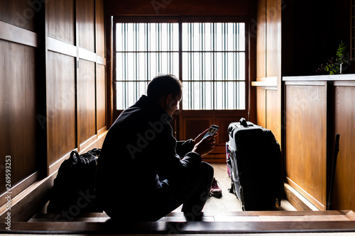 Traditional japanese machiya house or ryokan with sliding paper door entrance and light with man sitting holding phone architecture