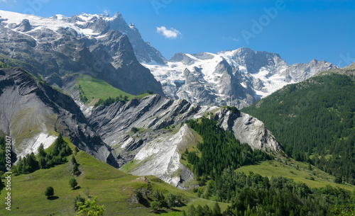 AERIAL  Flying across the vast green valley and towards spectacular glacier.