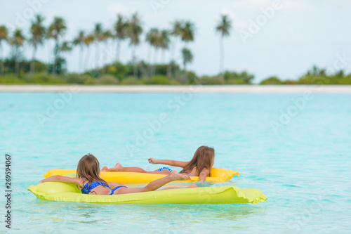 Adorable little girls on air inflatable mattress in the sea